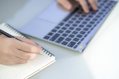 Evde çalışan bir kadın dizüstü bilgisayarla internette arama yapıyor, bilgileri tarıyor, elini klavyeye koyup kapatıyor.