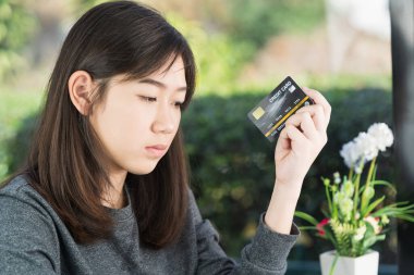 Kredi kartı gösteren ve online alışveriş için akıllı telefon tutan genç bir kadın, online alışveriş kavramı