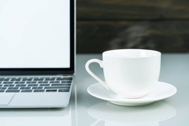 Laptop 'ın ön görüntüsü ve çalışma masasında ahşap arka planı olan kahve fincanı.