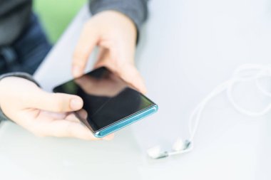 Kredi kartı tutan bir kadın ev ofisinin güvertesinde online alışveriş için akıllı telefon kullanıyor.