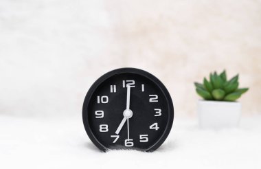 Masanın üzerindeki siyah alarm saatini ve küçük dekoratif ağaç vazosunu kapat.