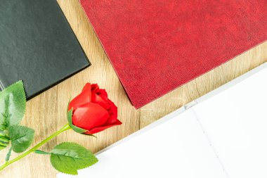 Kırmızı güllerin üst görüntüsü boş defter günlüğü ve ahşap masa üzerindeki ciltli gözlük, Sevgililer Günü konsepti.