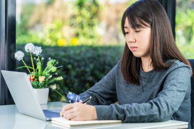 Genç bir bayan iş yerinde çalışmak için dizüstü bilgisayar kullanıyor, genç bir kız öğrenci evde ödev yapmak için dizüstü bilgisayar kullanıyor.