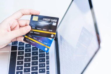 Çevrimiçi ödeme yapan kadınların ellerini kapatın, kredi kartı tutan kadınların elleri ve online alışveriş için laptop kullanın.