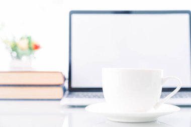 Güvertede boş ekran bilgisayarı olan bir fincan kahve, evde dizüstü bilgisayarı ve kahve fincanı olan bir işyeri, iş formu ev konsepti.