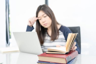 Genç kız öğrenci oturma odasında oturuyor ve internetten öğreniyor.