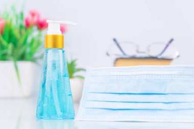 Alkol jeli şişesi ve cerrahi maske, güvertede antibakteri ve virüs koruması için tıbbi maske.