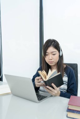 Genç kız öğrenci oturma odasında oturuyor ve internetten öğreniyor.