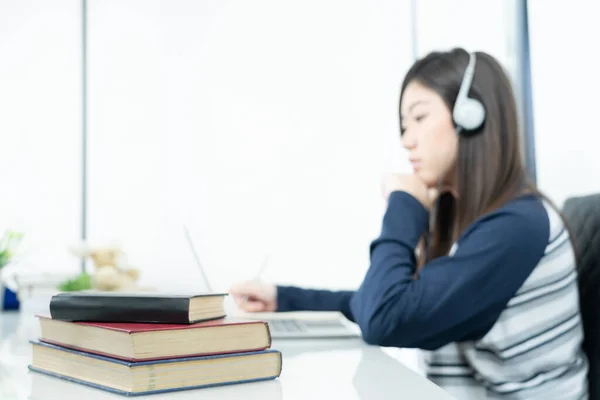 若い女性の長い髪のリビングルームに座って デスクでラップトップを使用してオンラインでヘッドフォン学習を身に着けています — ストック写真