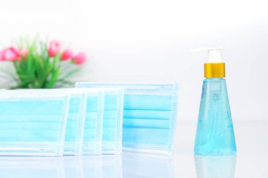 Güverte ajanı beyaz arka planda bakteri ve virüs koruması için cerrahi maske, tıbbi yüz maskeleri ve alkol jeli dezenfektan el (COVID-19)