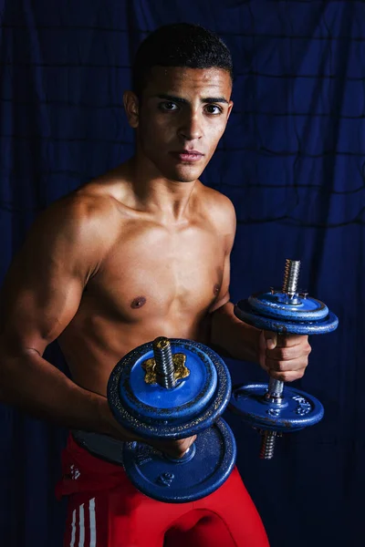 athlete raises cast iron dumbbells with his arms