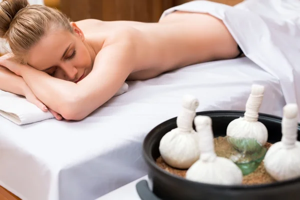 Massagem tailandesa com sacos de sal. Menina posando mentira — Fotografia de Stock