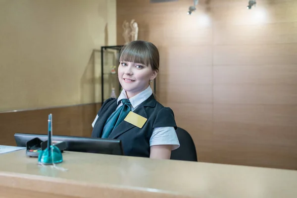 Recepción del hotel. Bonita anfitriona sonriendo a la cámara — Foto de Stock