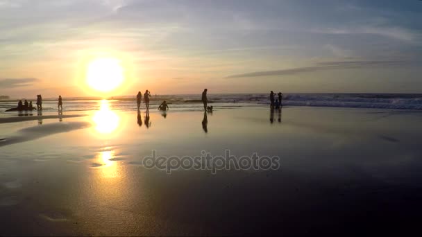 Вид людей, отдыхающих на пляже во время заката — стоковое видео
