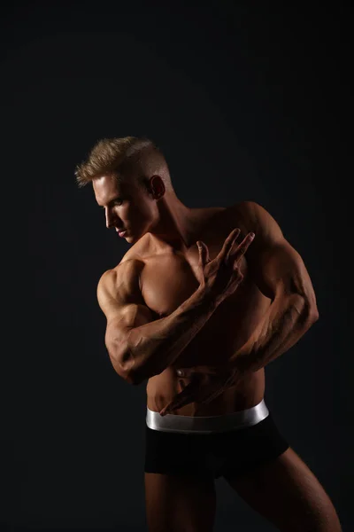 Sexig bodybuilder i trosor poserar i hans profil — Stockfoto