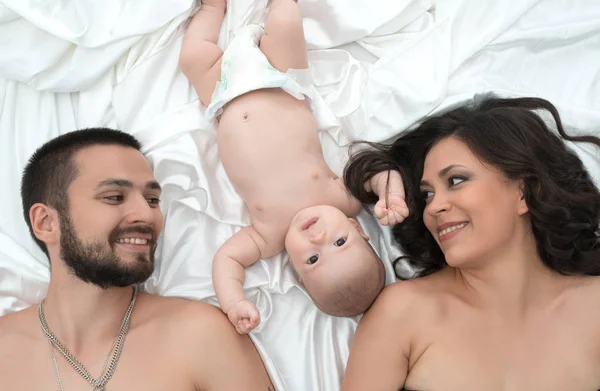 Loving parents with newborn baby in bed together — Stock Photo, Image