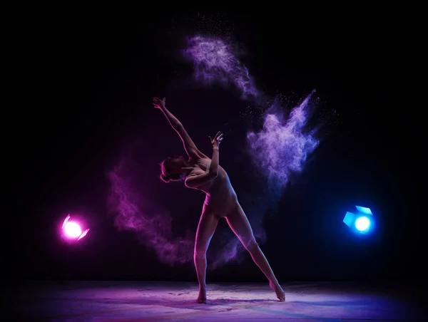 Gymnast in ecru bodysuit in cloud of colored dust — Stock Photo, Image