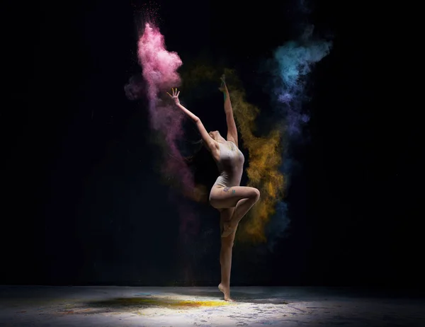 Gymnast in ecru bodysuit with colored dust around — Stock Photo, Image