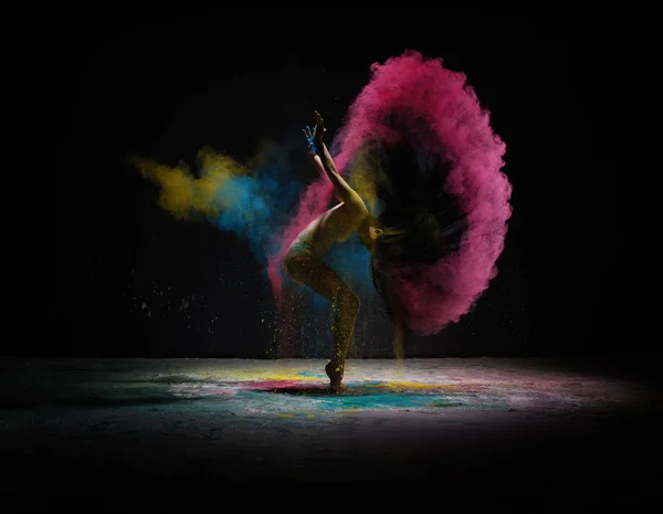 Танцовщица движется в облаке цветной пыли на сцене — стоковое фото