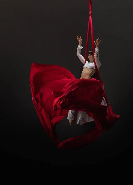 Досить молода гімнастка на червоних повітряних шовках в студії — стокове фото
