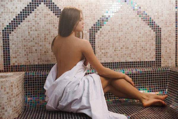 Topless meisje verpakt in een laken schot in de sauna — Stockfoto