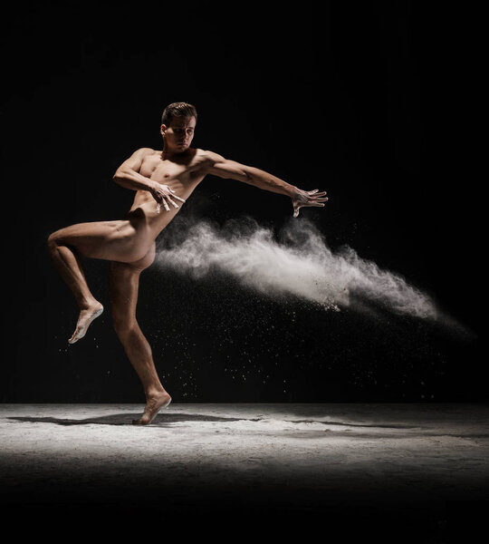 Nude man posing in white dust cloud studio shot