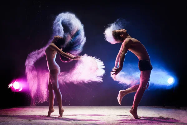 Sporty couple in color dust cloud studio shot — Stock Photo, Image