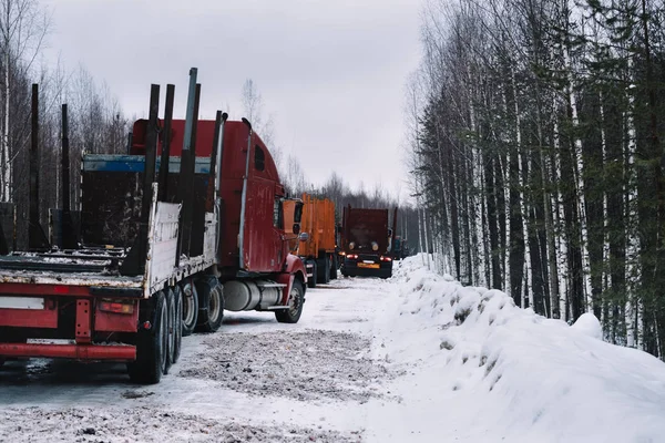 Vehículos largos vacíos en el camino de invierno entre bosques —  Fotos de Stock