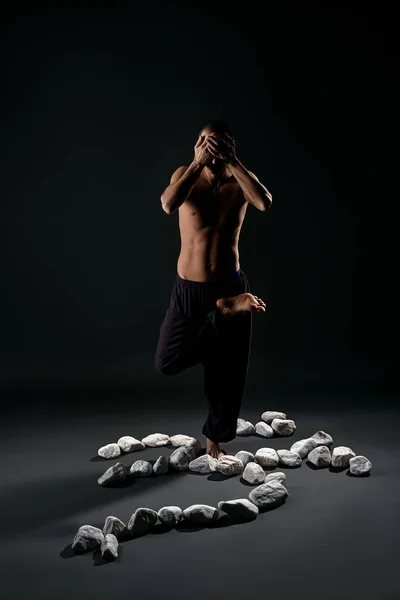 Mannen bor i yogaställning med vita stenar nära av — Stockfoto