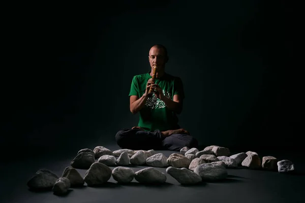 Hombre sentado en postura de yoga con piedras blancas cerca —  Fotos de Stock