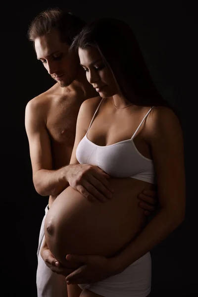 Беременная молодая женщина позирует со своим мужем — стоковое фото