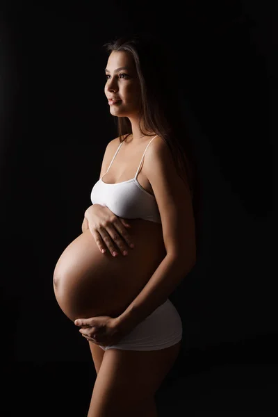Беременная молодая женщина позирует в нижнем белье в студии — стоковое фото
