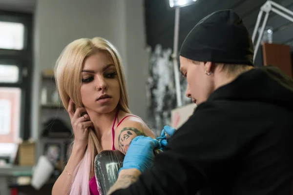Sexy blondýnka a tattoo master v práci ve studiu — Stock fotografie
