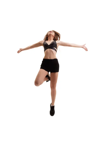 Спортивная сексуальная блондинка в черном топе, прыгающая в студии — стоковое фото