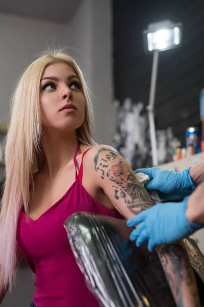 Artysta tattooist co tatuaż na ramieniu klienta — Zdjęcie stockowe