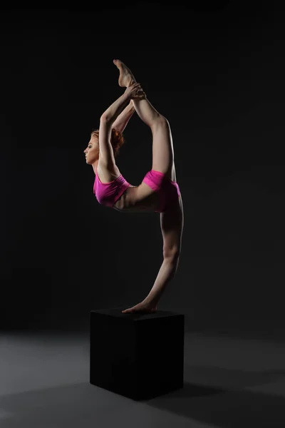 Güzel jimnastikçi ince bir şekilde küpün üzerinde duruyor. — Stok fotoğraf