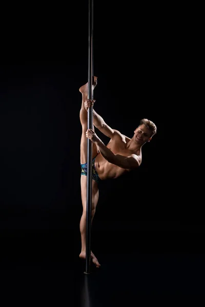 Junger hübscher, athletischer Mann beim Turnen auf einem Pylon — Stockfoto