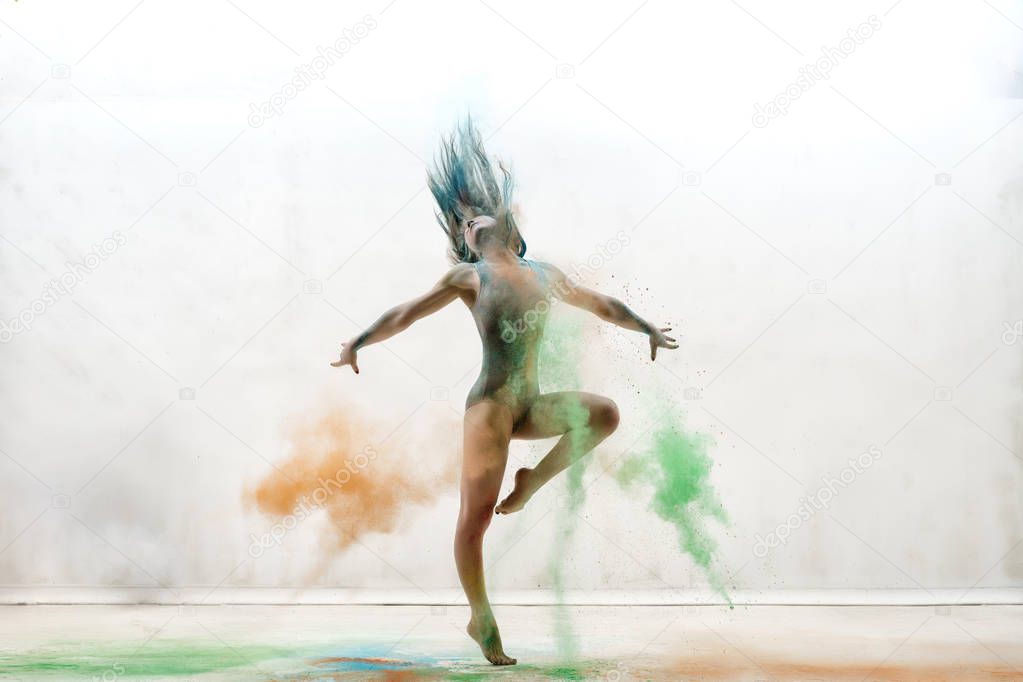 Sexy girl in a cloud of color dust studio portrait