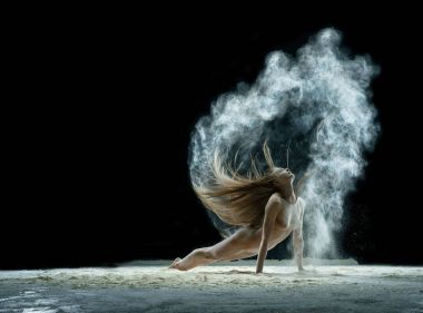 Beyaz toz bulutu içindeki seksi sarışın stüdyo portresi.