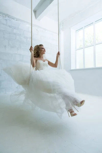 Prachtige jonge bruid op schommel in studio — Stockfoto