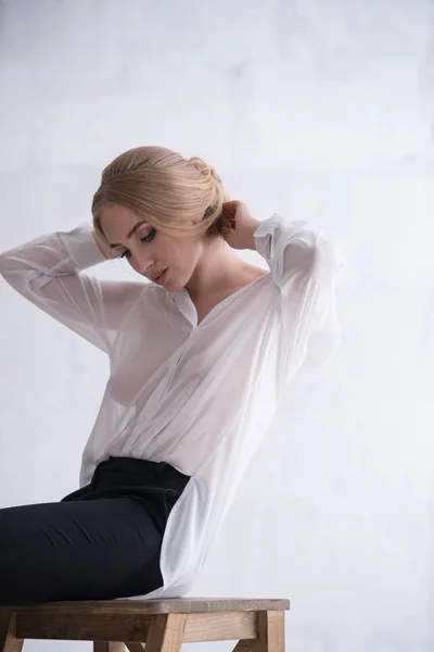Sexy vrouw in wit kantoor shirt poseren op stoel — Stockfoto