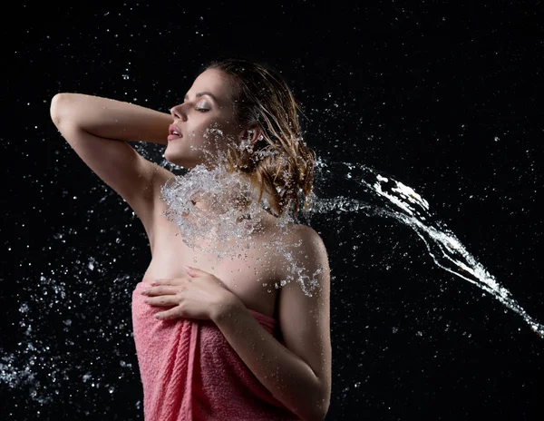 Chica disfrutando del chorro de agua disparó contra la pared negra — Foto de Stock