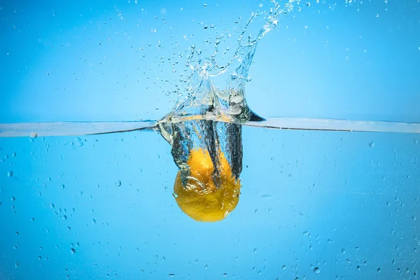 Single lemon being dropped in water