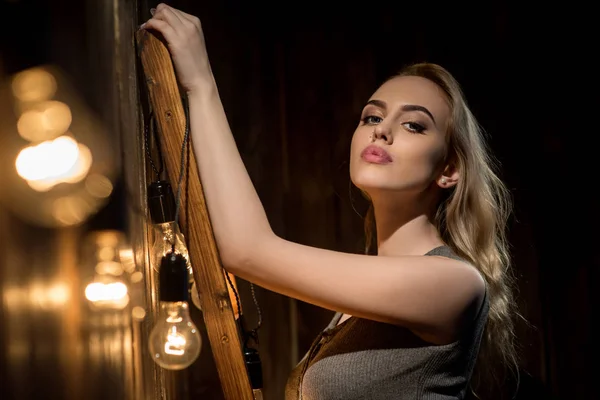 Blonde with long locks portrait near wooden wall