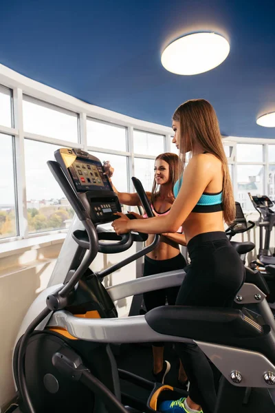 Young girls on exercise bikes installing programme — Stock Photo, Image