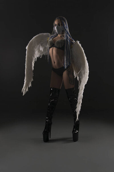 Slim girl with wings and in bdsm mask and belts
