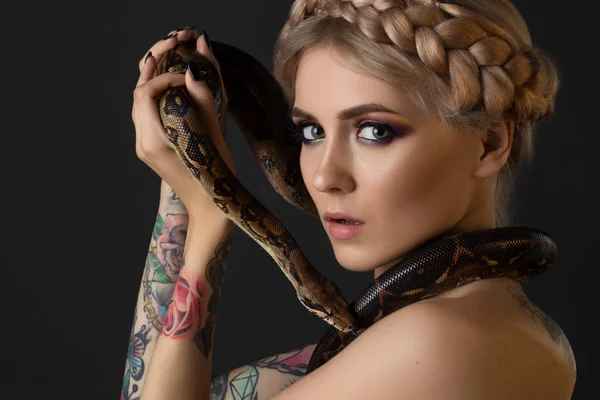 Wytatuowany blondynka z Pythona na czarnym tle — Zdjęcie stockowe