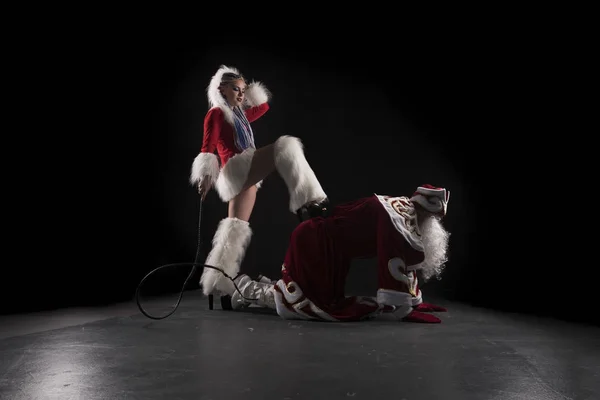 Donzela de neve com chicote e Papai Noel em seus joelhos tiro — Fotografia de Stock