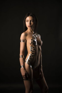 Çıplak esmer vücudu altın bant ile kaplı.