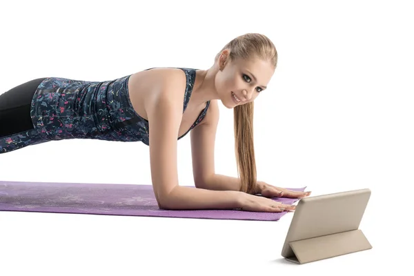 Jonge vrouw doet fitness op een mat geïsoleerd beeld — Stockfoto